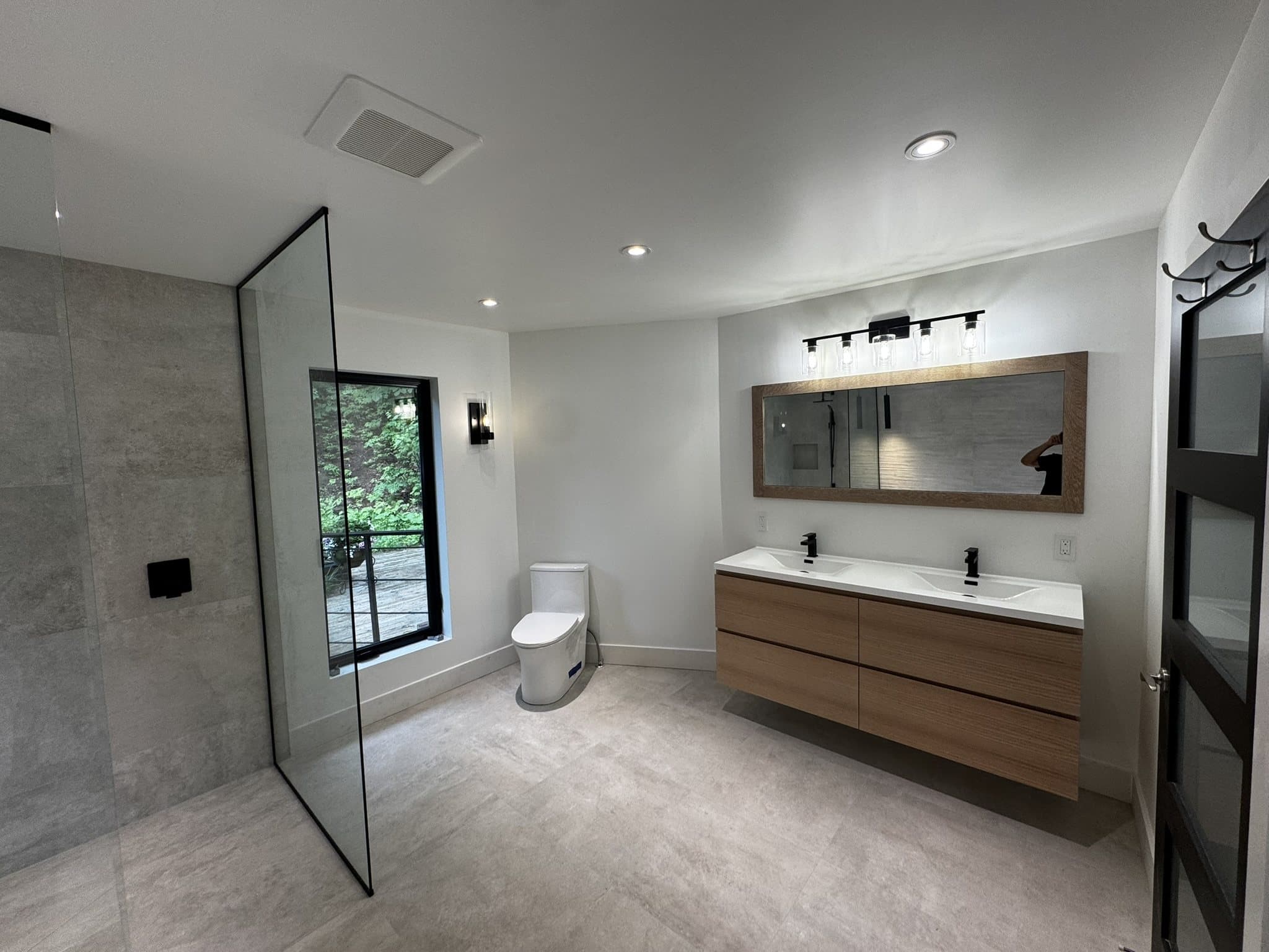Vanité double suspendue en bois et grand miroir dans une salle de bain rénovée