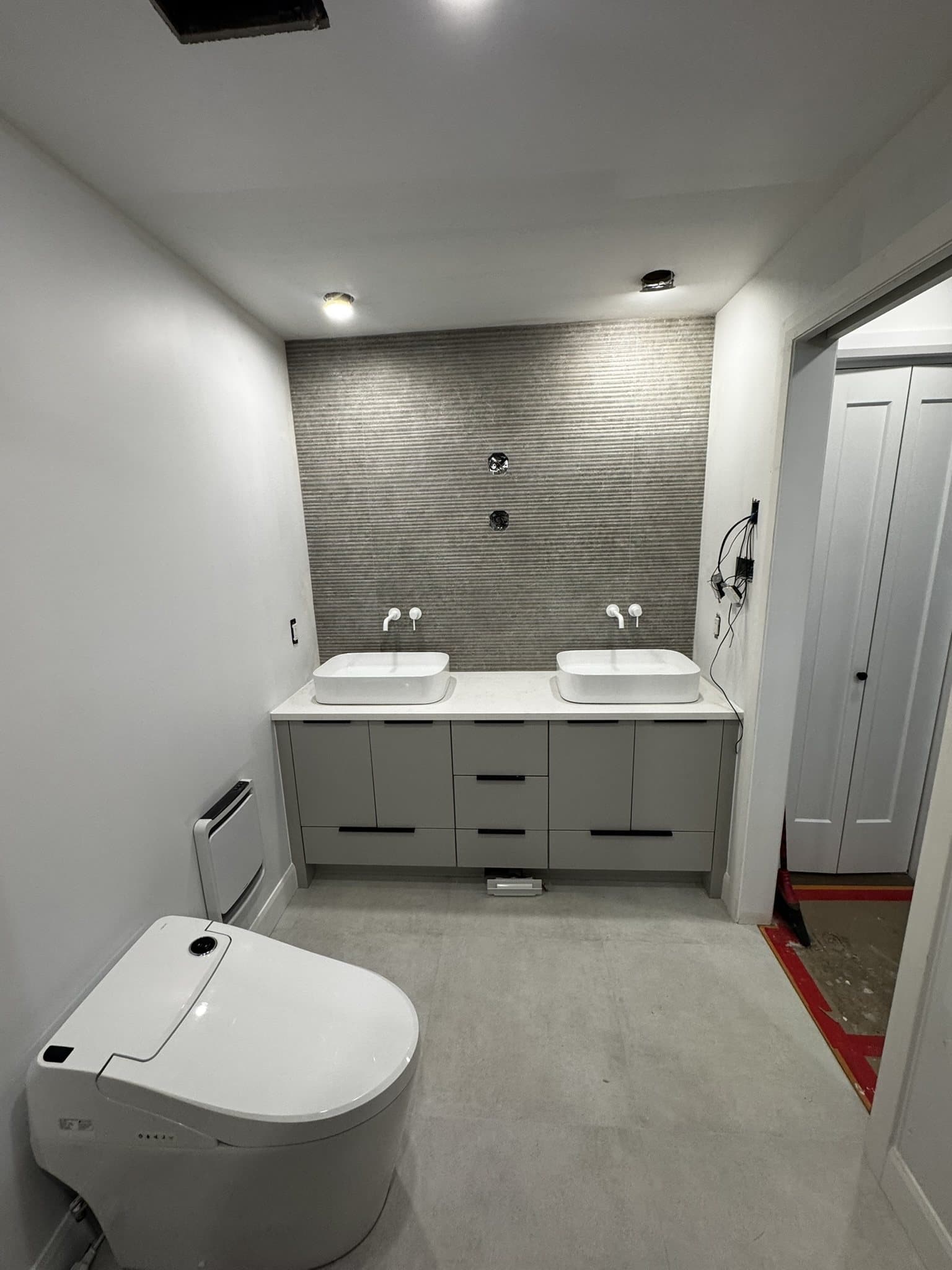 Vanité double et toilette devant un mur d’accent en céramique