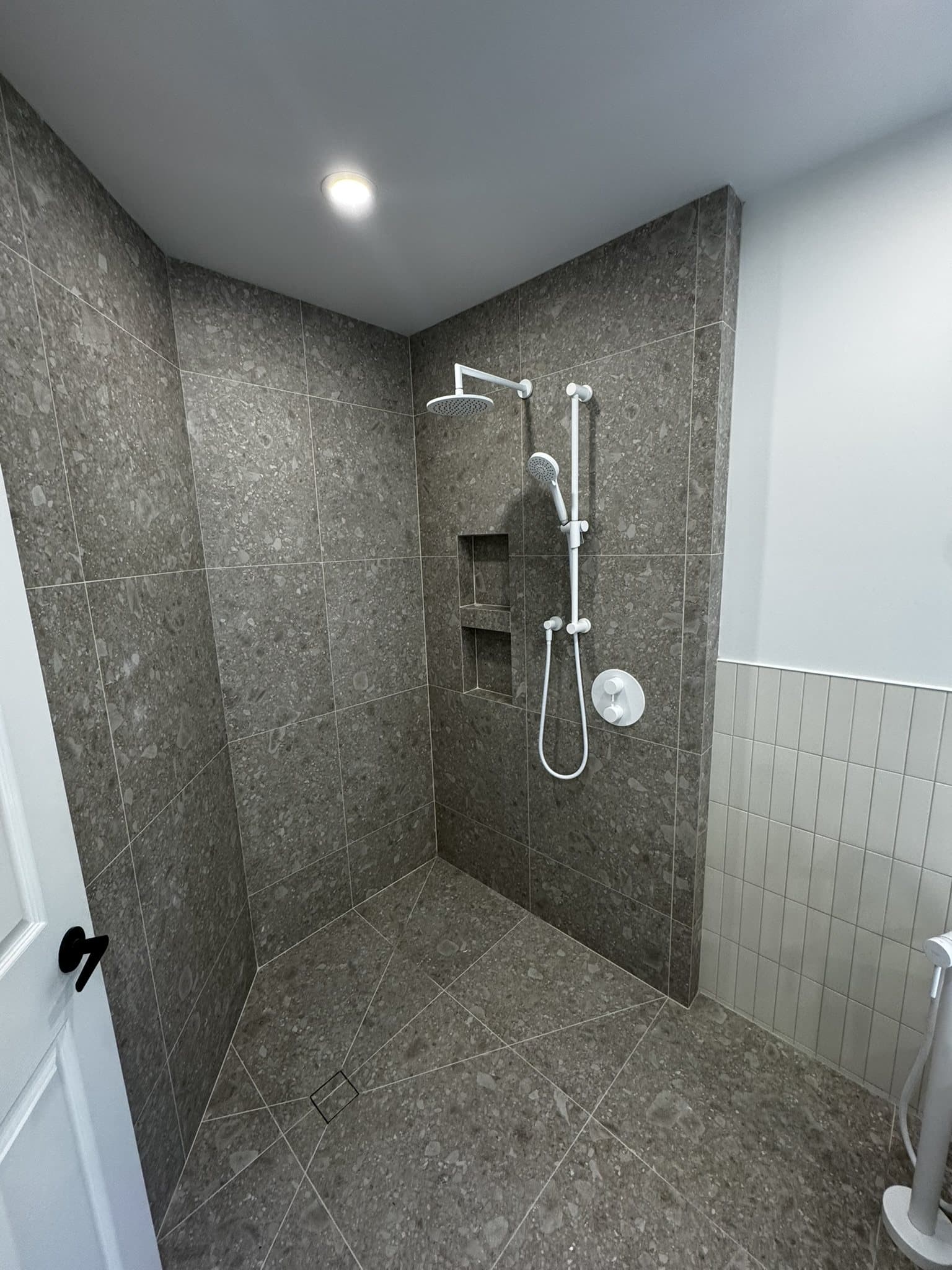 Douche à l’italienne en céramique effet terrazzo avec robinetterie blanche