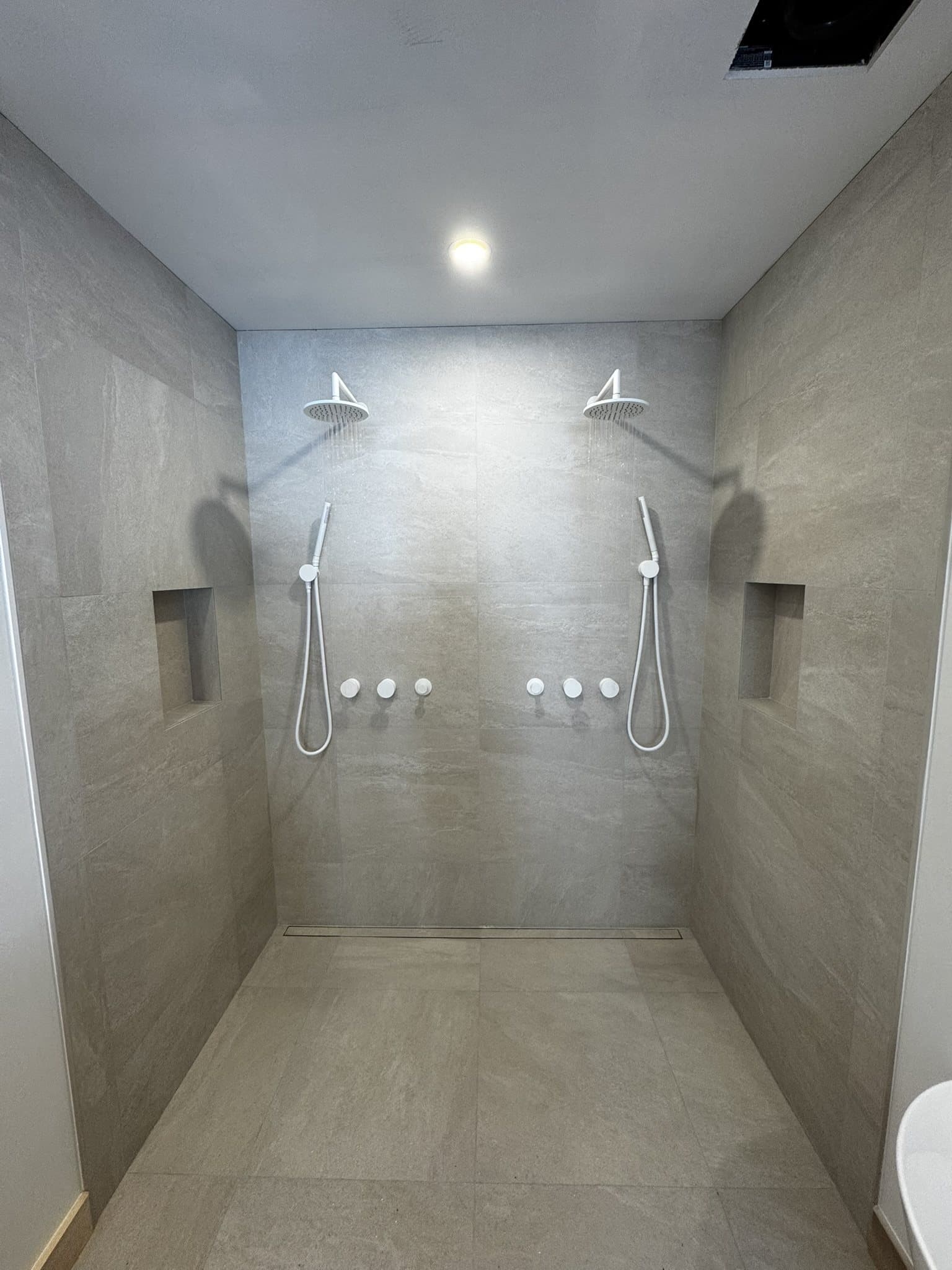 Douche à l’italienne à deux pommeaux avec niches encastrées