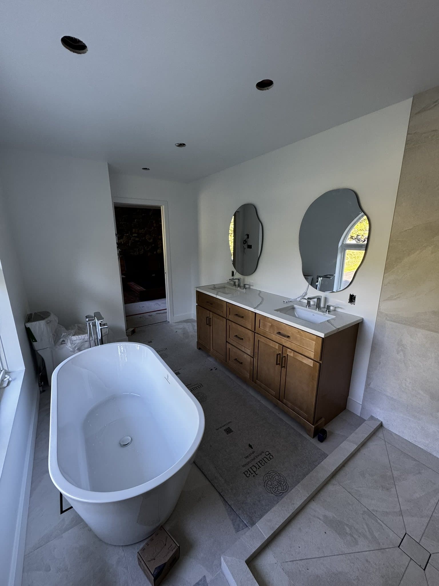 Salle de bain avec bain autoportant, vanité double et miroirs arqués